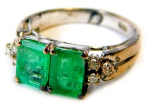 An emerald and diamond dress ring, set with two rectangular cut emeralds, each in four claw setting,