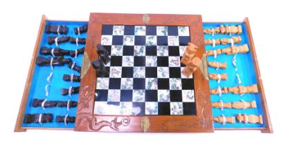 An Oriental chess set, in a hardwood case opening to reveal a chequered border, with pieces in