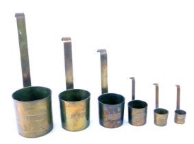 A set of six brass barrel measuring cups, each with arched hook handle, going from 1cl to half a lit