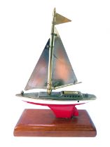 A mid century novelty boat table lighter, with brass sail, red and white painted hull, on a rectangu