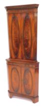 A Reprodux mahogany and flamed mahogany standing corner cabinet, the top with a dentil moulded edge