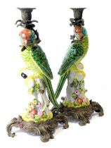 A pair of Adele Carey porcelain and cast metal candlesticks, modelled as a green parrot holding cast