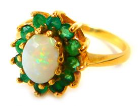 A 9ct gold emerald and opal cluster ring, the central oval opal in claw setting, surrounded by emera