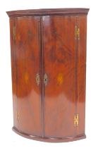 A George III flamed mahogany bow front corner cabinet, the top with a moulded edge above two doors,