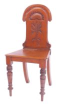 A Victorian walnut hall chair, the solid back carved with a fan and floral motif, solid seat on fron