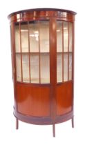 An Edwardian mahogany bow front display cabinet, the top with a moulded edge above a panelled half g