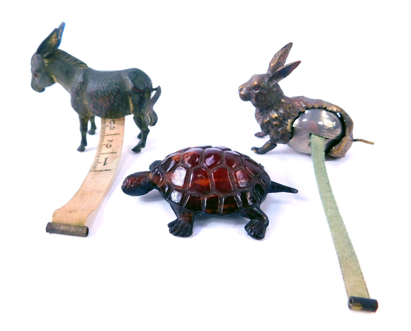 Three novelty tape measures, modelled as a donkey, hare, and a tortoise, the donkey 5.5cm high.