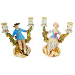 A pair of late 19thC Meissen porcelain candelabra, modelled as a gallant and lady, seated within a t