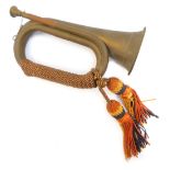 A copper and brass bugle, with orange, yellow and blue rope work frogging, 29cm long.
