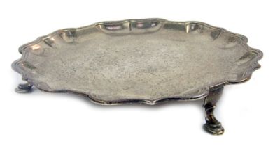 A Victorian silver card tray, with piecrust border raised on three hoof feet, Ogden's Harrogate and