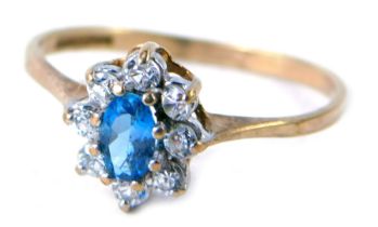 A 9ct gold cluster ring, the central stone set with an oval pale blue stone surrounded by CZ, each i