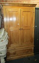 A waxed pine double wardrobe, the top with a moulded cornice above two panelled doors enclosing a si