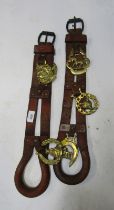 Two horse brasses, each on brown leather strap.