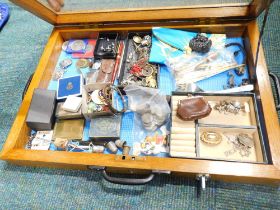 A curio cabinet and contents, to include Chinese tokens, Victorian style brooch, thimbles, collector