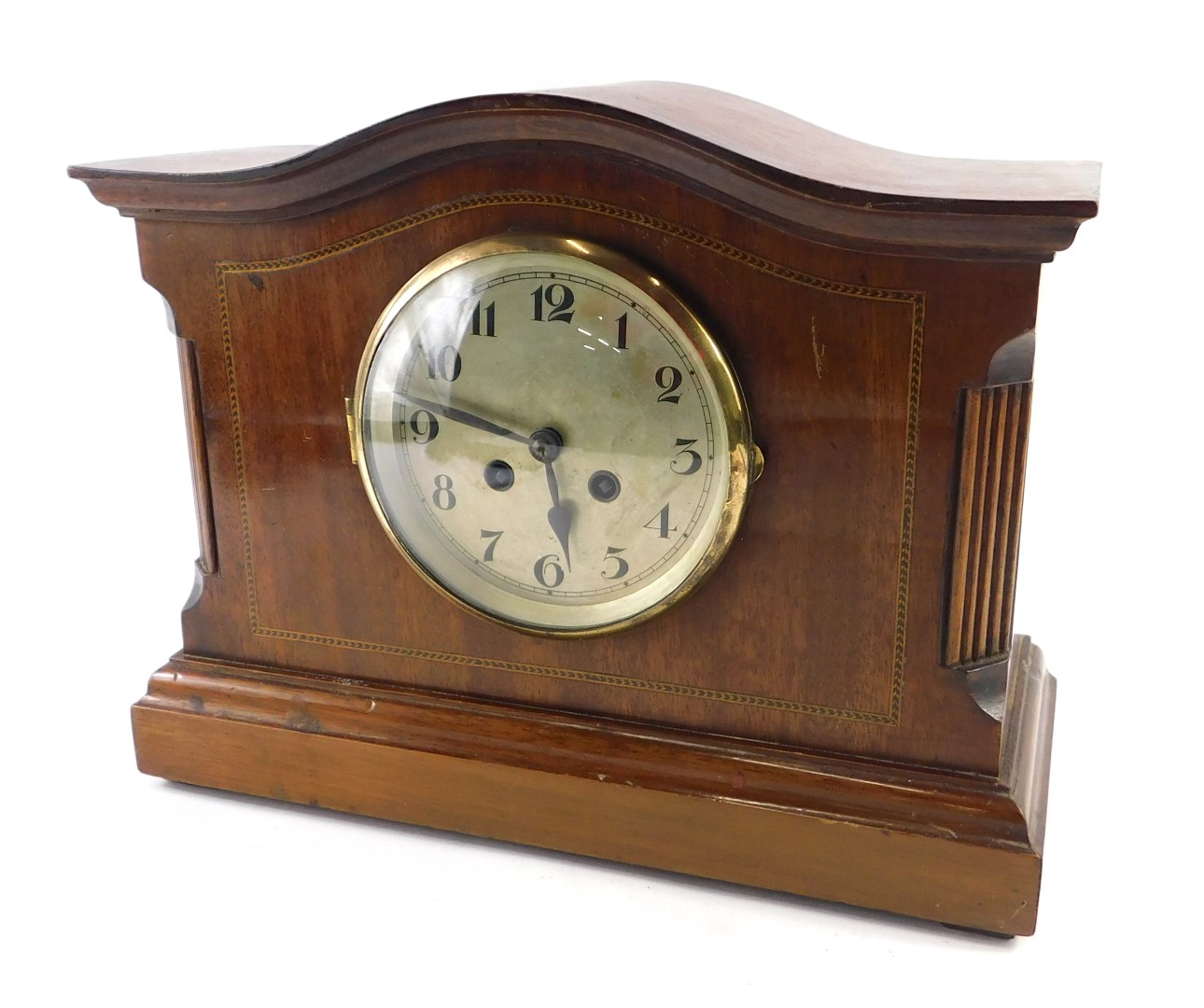 An Edwardian mahogany and chequer banded mantel clock, with a shaped top, silvered dial, on a plinth