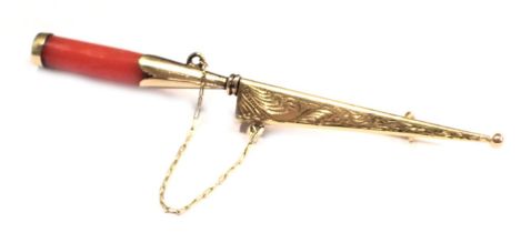 A dagger brooch, with a coral handle, in a yellow metal casing, the stainless steel blade