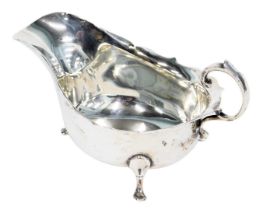 A George V silver sauce boat, with a fluted border and arched handle on tripod claw feet, Birmingham