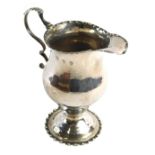A George IV silver helmet shaped cream jug, with beaded borders, a domed foot and a scroll handle wi