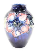 A Moorcroft small clematis pattern bud vase, decorated with pink flower, on a blue ground, with blue