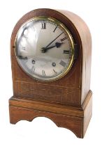 A 19thC mahogany and boxwood strung mantel clock, with a silvered dial, and an arched case, 30cm hig