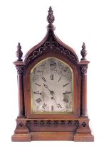 A Victorian gothic mantel clock, the oak case decorated with scrolls, pillars, and leaf carved finia