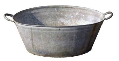 A galvanized wash tub, of oval form with two handles, 29cm high, 69cm wide, and 50cm deep.
