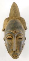 A Baule Mblo spiritual portrait mask with elaborate coiffure, Cote D'Ivoire, 38cm high.