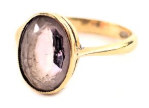 A topaz dress ring, the oval pink topaz in a rub over setting on a plain band, yellow metal stamped