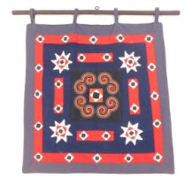 Tribal Art. An embroidered panel, on a navy ground with red star border, mahogany pole, 79cm high, 8