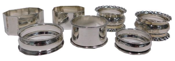 Seven silver napkin rings, comprising a pair of George V napkin rings with pie crust borders and scr