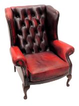 A Chesterfield red wingback armchair, in button back on mahogany legs.