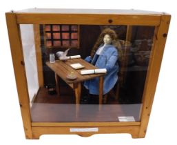 A diorama model of Samuel Pepys, modelled seated at a table, in fitted perspex and stained pine case