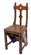 A Victorian Gothic oak metamorphic library chair, with a shaped back solid seat.