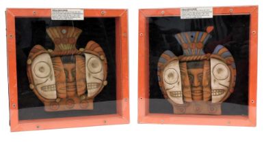 Two replica Aztec triple death masks, each in red painted and perspex cases, 34cm wide.