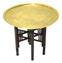 An Egyptian occasional table, the brass top engraved with hieroglyphic figures, on folding turned ba