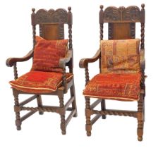 A pair of carved oak elbow chairs, in Carolean style, each with a panelled back, spirally turned sup