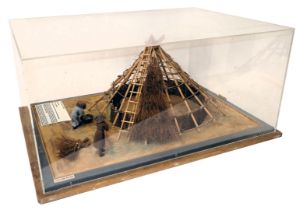 A diorama model of an Iron Age dwelling, modelled with people, etc., in wooden perspex case, 44cm wi