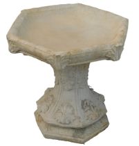 A reconstituted stone birdbath, of hexagonal form with acanthus leaf decoration, on hexagonal base,