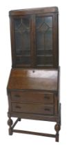 A 1920's oak bureau bookcase, the top with two glazed doors the base with a fall and two drawers on