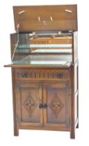 An Old Charm style oak cocktail cabinet, the double hinged top enclosing a mirrored interior, carved