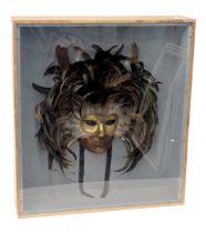 A decorative Venetian mask, embellished with black feathers, in pine and perspex case, 64cm high, 57