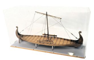 A model of a Viking ship, with shallow hull, carved ends, a brooch model figure, etc., in perspex ca