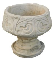 A reconstituted stone fleur de lys pattern urn, stylised with three petal design, on a circular foot