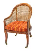 A Regency mahogany bergere library chair, with a moulded frame, caned back and sides, striped squab