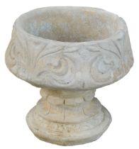 A reconstituted stone fleur de lys pattern urn, stylised with three petal design, on a circular foot