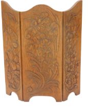 An Arts and Crafts carved oak triple spark guard, decorated with tulips and other flowers, 77cm high