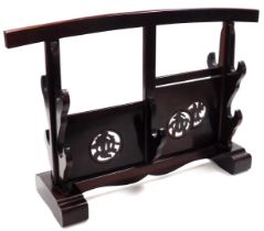 A Japanese hardwood sword stand, with carved motifs, and brackets for four swords, raised on block f