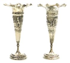 A pair of early 20thC Thai bud vases, of trumpet form, repousse decorated with a central band depict