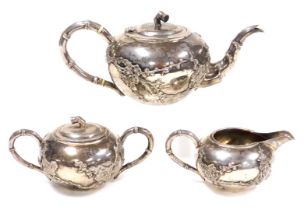 A late 19thC Chinese white metal three piece tea set, with raised decoration of prunus, maker's mark