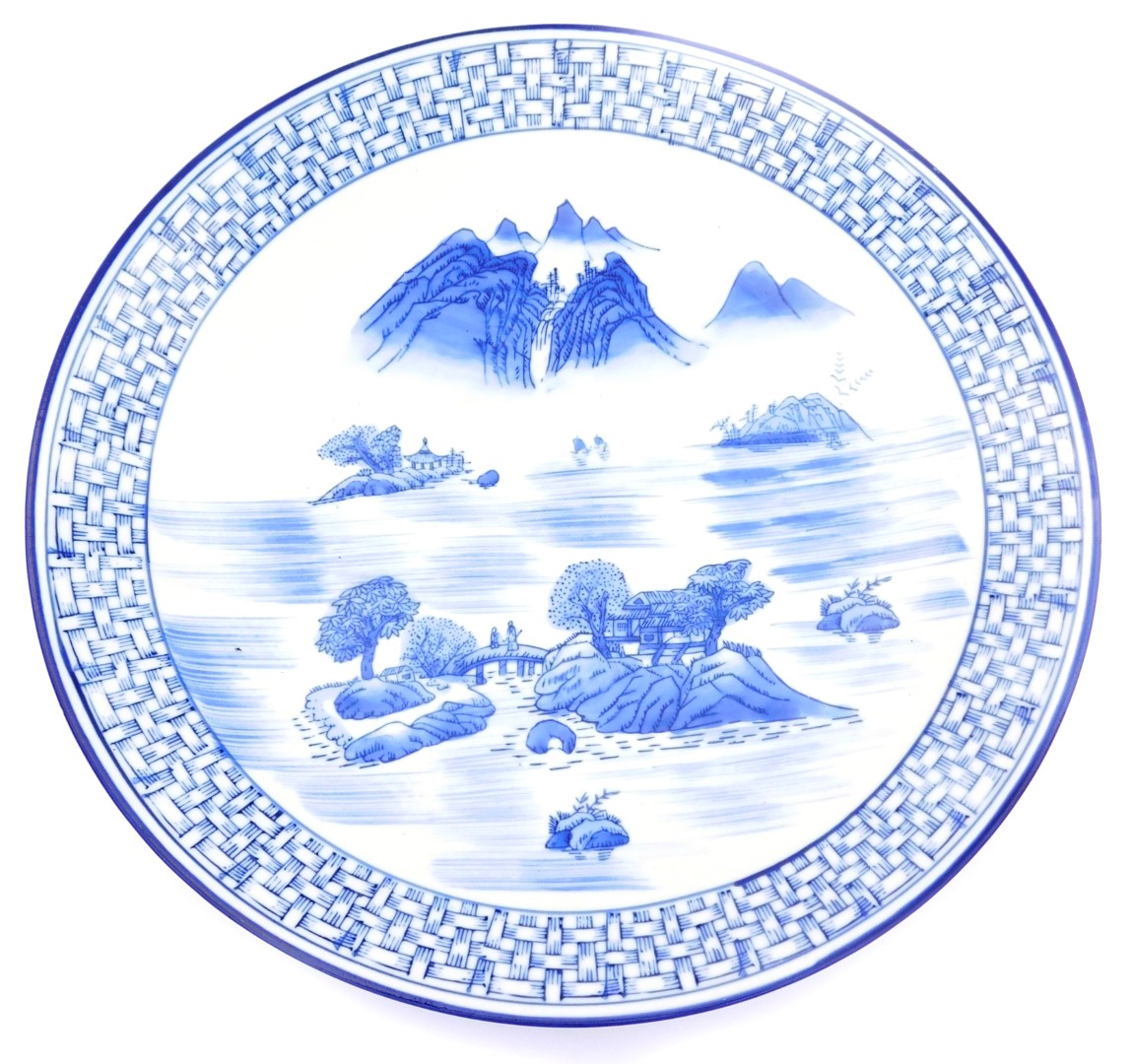 A late 20thC Japanese blue and white porcelain charger, decorated with figures in a lake and mountai